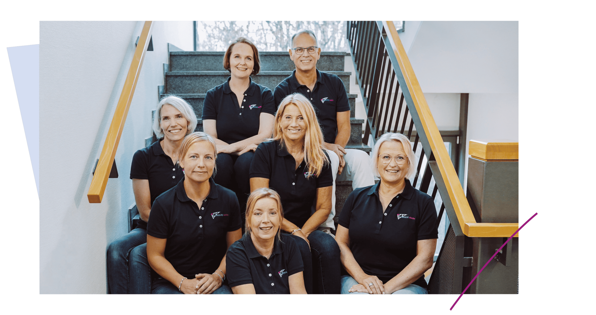 Team Steenbeker-Weg-klein Das Bild zeigt ein Team von sieben Personen, die lächelnd auf einer Treppe posieren. Alle Mitarbeiter tragen schwarze Poloshirts mit einem Logo. Der Hintergrund zeigt eine helle Treppe und Fenster, die viel Tageslicht hereinlassen.